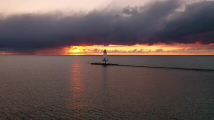 Wall Mural - beautiful sunset aerial panning across in front of the ludington breakwater lighthouse as the sun re