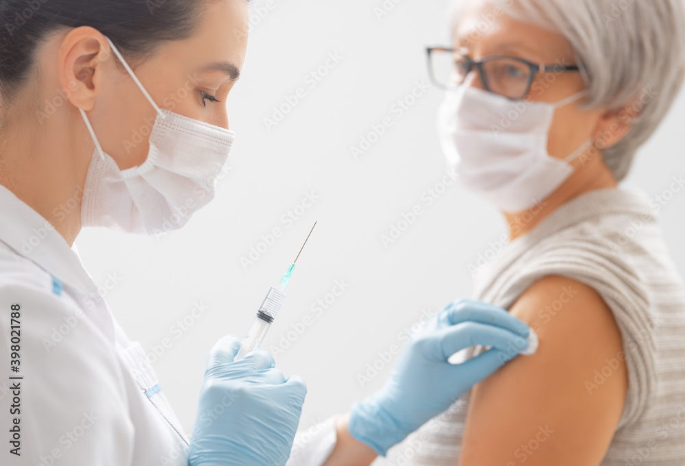 Doctor giving a senior woman a vaccination - obrazy, fototapety, plakaty 