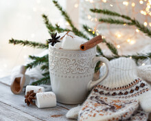 Winter Hot Drink. Cozy Home Composition With White Mug With Chocolate And Marshmallow, Cinnamon. Knitted Mittens, Christmas Lights, Wooden Background. Festive Holiday Atmosphere, Family Spirit. Close