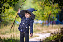 Toddler Boy In Pointed Hat Playing With Magic Wand Outdoors. Little Wizard. Halloween Concept