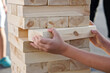 The hands of a child taking one block from a tower during a street game of giant Jenga. Outside the home