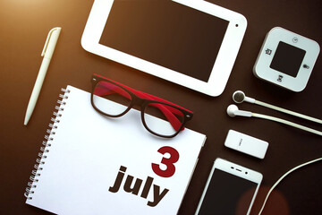 July 3rd. Day 3 of month, Calendar date. Office workplace with laptop, notebook, office supplies and stationery on brown back. Summer month, day of the year concept.