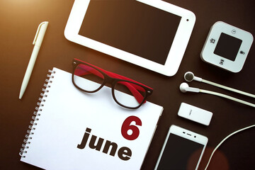 June 6th. Day 6 of month, Calendar date. Office workplace with laptop, notebook, office supplies and stationery on brown back. Summer month, day of the year concept.