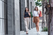 © lukyeee_nuttawut - Young shopaholic friends women friends walking and carry shopping bags in the street city with happy and smiling.