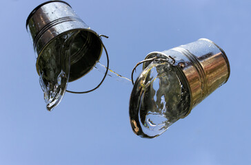 A falling buckets splashes water, on a background of blue sky.