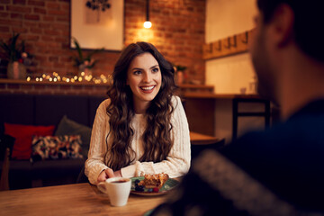 Wall Mural - Happy couple sitting in cafe during Christmas time