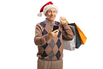 Wall Mural - Elderly man with a mobile phone and shopping bags wearing a santa claus hat