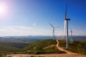 Wall Mural - reflections of the sun's rays on wind turbines in a mountain wind farm in sardinia. renewable energy