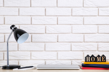 Poster - Laptop computer with electrical lamp and books on brick wall background