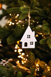 Vertical atmospheric photo Christmas decoration with a house figure on a Christmas tree with lights and balls. White House. Purchase of real estate, housing.
