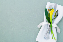 Spring Table Place Setting That Is Elegant And Modern With Copy Space. It's A Horizontal Flat Layout With A Yellow Calla Lily, Silverware, And A Cloth Napkin.