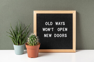 Wall Mural - Old Ways Won't Open New Doors. Motivational quote on letter board, cactus, succulent flower on white table. Concept inspirational quote of the day. Front view