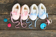 © Viktoriia M - 2021 new year written laces of children's shoes and pacifier on old wooden background. Top view. Flat lay.