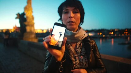 Poster - A woman blogger shows a photo on the phone screen in the evening in the city. Tells the oral history of photography.