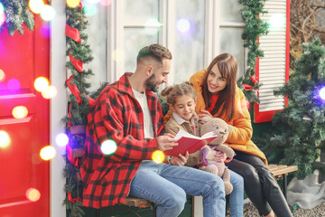 Poster - Happy family reading book near house decorated for Christmas