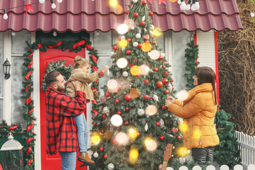 Poster - Happy family decorating Christmas tree near house outdoors