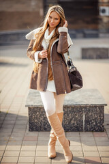 fashion outdoor photo of gorgeous sensual woman with blond hair in elegant clothes and luxurious coat, walking by winter city