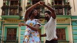 Happy afro dancers curling in latino dance in city. Couple dancing on street