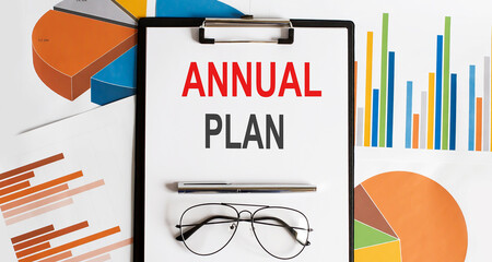 Poster - ANNUAL PLAN text . Conceptual background with chart ,papers, pen and glasses