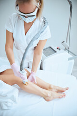 Wall Mural - Cosmetician pointing the laser device at the patient skin