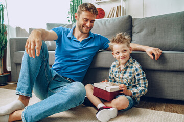 Father gives a present in box to his little son