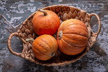 Orange Little Pumpkins In A Wicker Basket On An Old Gray Background. Copy Space, Halloween Design.