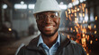 © Gorodenkoff - Happy Professional Heavy Industry Engineer/Worker Wearing Uniform, Glasses and Hard Hat in a Steel Factory. Smiling African American Industrial Specialist Standing in a Metal Construction Manufacture.