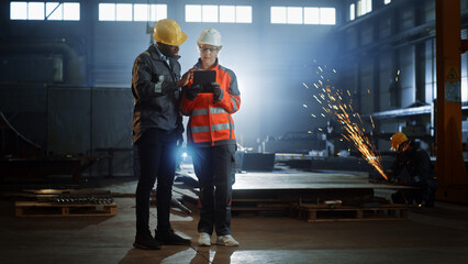 Aufkleber - Two Heavy Industry Engineers Stand in Steel Metal Manufacturing Factory, Use Digital Tablet Computer and Have a Discussion. Black African American Industrial Specialist Talk to Female Technician.