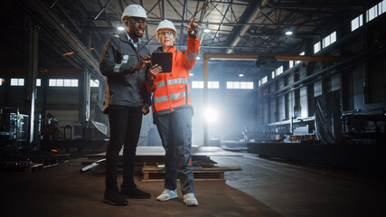 Aufkleber - Two Heavy Industry Engineers Stand in Steel Metal Manufacturing Factory, Use Digital Tablet Computer and Have a Discussion. Black African American Industrial Specialist Talk to Female Technician.