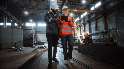 Aufkleber - Two Heavy Industry Engineers Walk in Steel Metal Manufacturing Factory, Use Digital Tablet Computer and Have a Discussion. Black African American Industrial Specialist Talk to Female Technician.