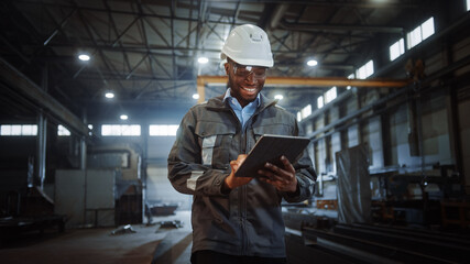 Aufkleber - Professional Heavy Industry Engineer/Worker Wearing Safety Uniform and Hard Hat Uses Tablet Computer. Smiling African American Industrial Specialist Walking in a Metal Construction Manufacture.