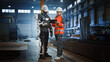 © Gorodenkoff - Engineer and Manual Labor Worker in a Bionic Exoskeleton Prototype Check Development Test Results on a Tablet. Heavy Industry Factory Engineers Discuss Warehouse Work and Futuristic Technology.