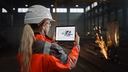 Wall Mural - Professional Heavy Industry Engineer Uses Tablet Computer for Augmented Reality Render with Interactive Turbine Engine Blueprint. Female Industrial Specialist Working in a Metal Manufacture Warehouse.