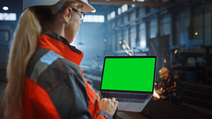 Aufkleber - Professional Heavy Industry Engineer Uses Laptop Computer with Green Screen Mock Up Display. Female Industrial Specialist Working in a Metal Manufacture Warehouse with Sparks in the Background.