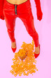 © Porechenskaya - Fast Food creative concept. Minimal art. Girl in red patent leather pants and shoes with corn cheese rings. Home party fashion style