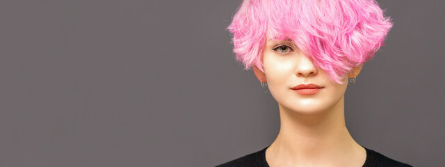 Portrait of fashion model young woman with stylish dyed pink hair in black clothes on dark background