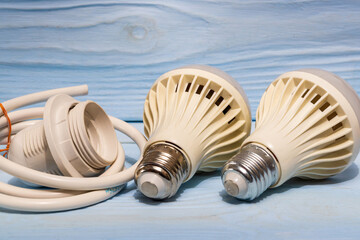 Two energy saving light bulbs and spare parts for installation on background of blue boards.