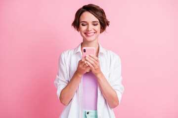 Poster - Photo of charming adorable young woman dressed white shirt looking modern gadget isolated pastel pink color background