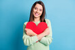 Photo of lovely young girl cuddle red paper heart figure toothy smile wear green sweater isolated blue color background