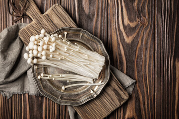 Fresh golden needle mushroom or enoki on silver vintage plate and wooden cutting board