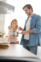 Wall Mural - Daughter Helping Father To Cook Meal In Kitchen.