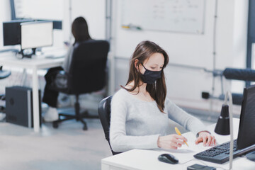 Woman wearing protective mask in office