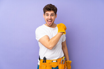 Wall Mural - Young electrician man over isolated on purple background celebrating a victory