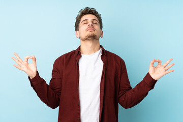 Wall Mural - Young caucasian man isolated background in zen pose