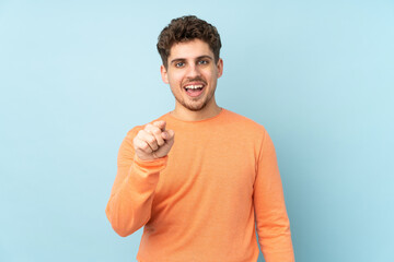 Wall Mural - Caucasian man isolated on blue background surprised and pointing front