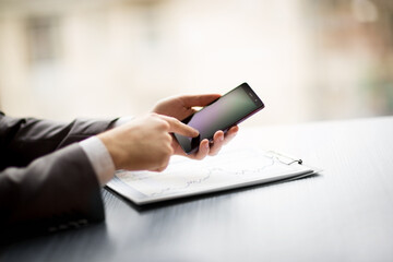 Wall Mural - businessman using his smartphone to work with financial data.