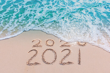 Wall Mural - message year 2020 replaced by 2021 written on beach sand background. good bye 2020 hello to 2021 hap