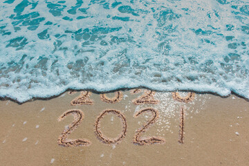 Wall Mural - message year 2020 replaced by 2021 written on beach sand background. good bye 2020 hello to 2021 hap