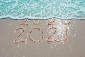Wall Mural - message year 2020 replaced by 2021 written on beach sand background. good bye 2020 hello to 2021 hap