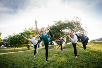 A group of people do yoga in the Park at sunset. Healthy lifestyle, meditation and Wellness